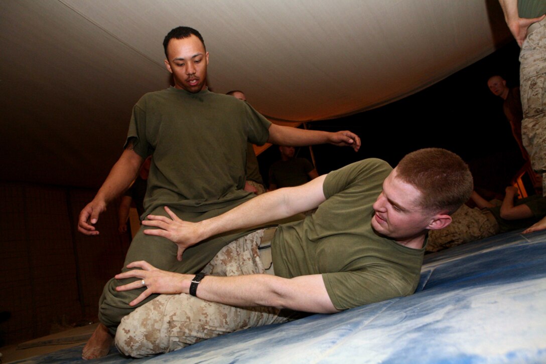 Cpl. Jeremy M. Wright, a chemical, biological, radiological, nuclear defense specialist, performs a technique he was taught, while Cpl. Bryan Y. Prevost, a personnel clerk, provides resistance at Combat Outpost Haditha, Iraq, May 4. Both Marines are with 3rd Battalion, 4th Marine Regiment, Regimental Combat Team 5. Marines with 3rd Bn., 4th Marines, have been practicing the Marine Corps Martial Arts Program as well as other forms of martial arts.