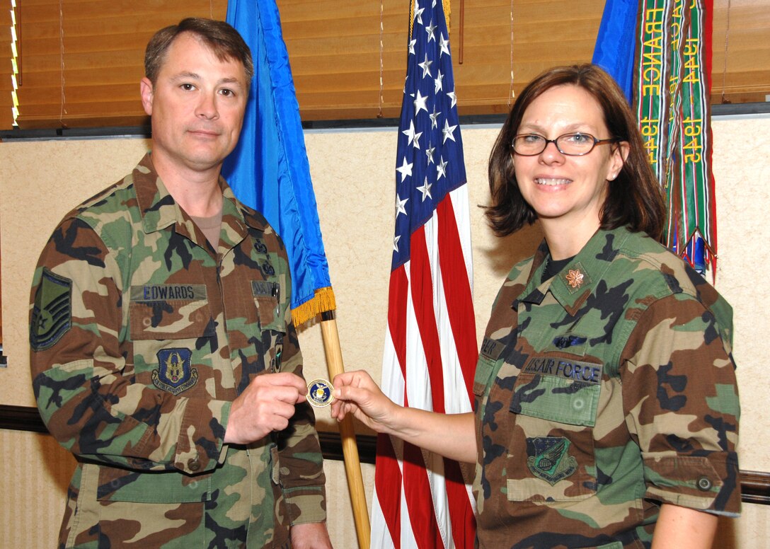 SEYMOUR JOHNSON AIR FORCE BASE, N.C. -- Chaplain Carol Yeager presents the first 916th Chaplain's Coin to Senior Master Sgt. Tim Edwards. Sgt. Edwards was instrumental in helping the 916th chaplain's office achieve numerous successes over the past several years before transferring to the 22nd Air Force Safety Office. The coin shows the state of North Carolina with a lighthouse clearly pointing to Seymour Johnson and the KC-135R Stratotanker. U.S. Air Force photo/TSgt. Gillian Albro