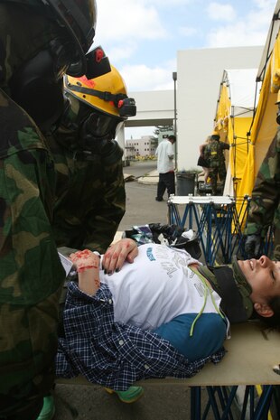Navy Petty Officer 1st class Michael Wall, decontamination triage officer, Headquarters and Service Company, Chemical Biological Incident Response Force, II Marine Expeditionary Force, escorts a simulated victim to the decontamination line May 4 during exercise Ardent Sentry 08. The exercise is the annual North American Aerospace Defense Command and United States Northern Command Defense Support of Civil Authorities exercise incorporated into NLE 2-08.