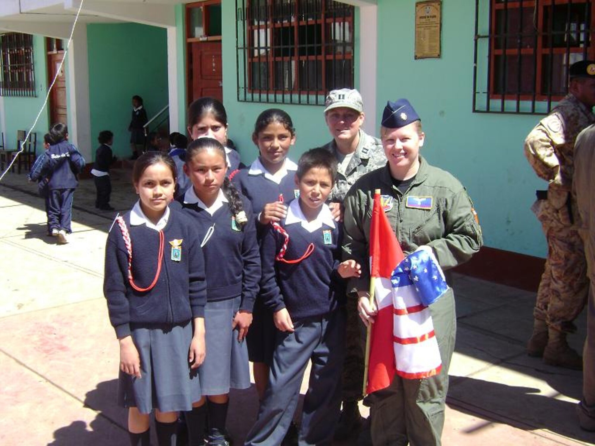 Maj. Theresa Goodman, 355th Aerospace Medicine Squadron flight surgeon and lead provider, and Capt. Erin Lagen, 355th Aerospace Medicine Squadron medical readiness flight commander and team lead pose for a photo after receiving a homemade American and Peruvian flag during opening ceremonies at Boanos De Inca School in Cajamarca, Peru. (Courtesy photo)