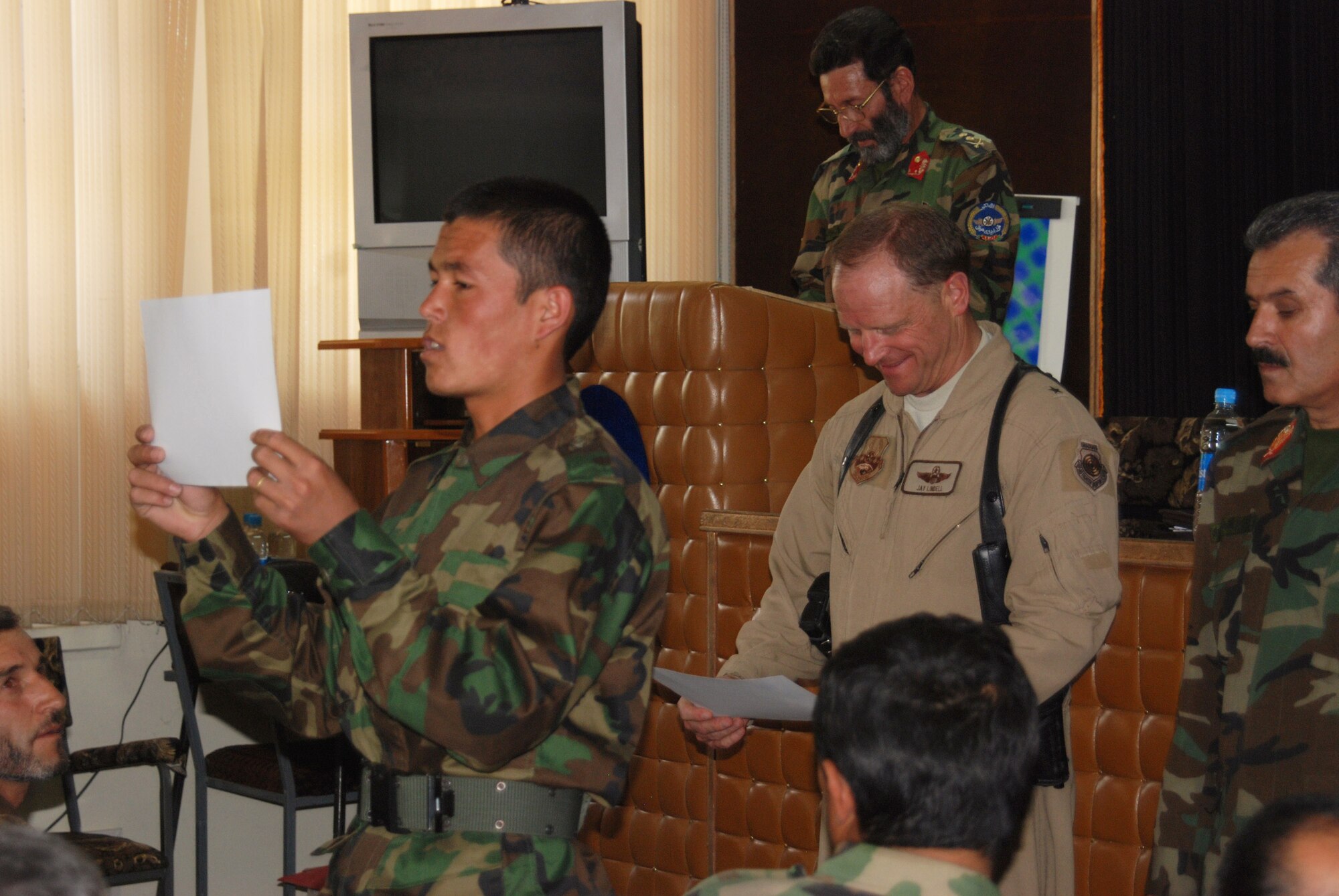 Brig. Gen. Jay H. Lindell passes out graduation certificates to the students of the Afghan National army air corps April 30. Graduating students learned aircraft safety, computer instruction, the history of the air corps, logistics and equipment maintenance. The graduates will now join Afghan National Security Forces throughout Afghanistan. (U.S. Navy photo/Petty Officer 1st Class Douglas Mappin) 