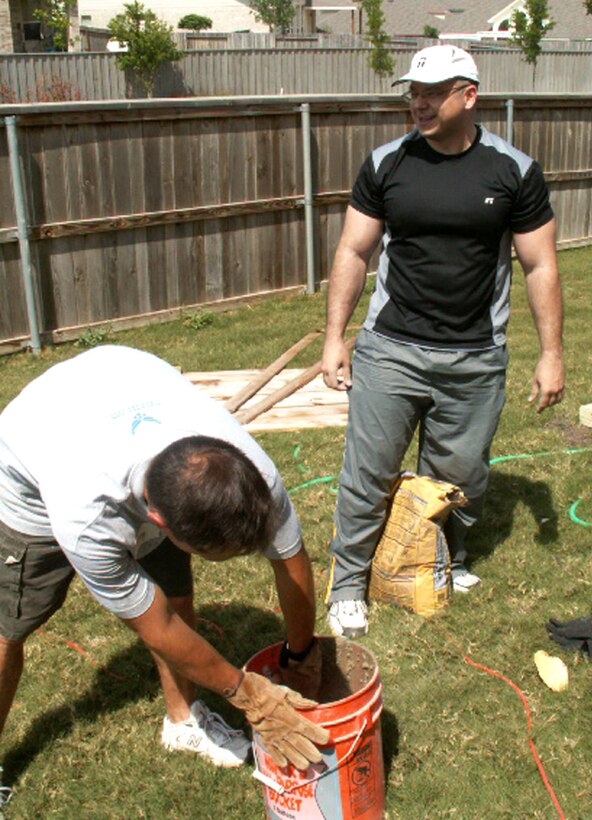 Master Sgts. Tracy Deason (left) and Angel Espinosa (right), personnelists at the Air Force Personnel Center, Randolph Air Force Base, Texas, debate the water to cement ratio while participating in Operation Homefront. Volunteers from AFPC's Top 3 Association built a gate to provide better access between the front and back yards for Tech. Sgt. Israel Del Toro, an Airman recovering from wounds sustained during a roadside bombing in Afghanistan, December 2005. (US Air Force photo/Master Sgt. Kat Bailey)