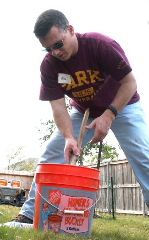 Master Sgt. Alex McCullough, a personnelist at the Air Force Personnel Center, Randolph Air Force Base, Texas, mixes cement to stabilize a fence post as part of a volunteer effort supporting Operation Homefront. Volunteers from AFPC's Top 3 Association helped craft a gate to provide better access between the front and back yards for Tech. Sgt. Israel Del Toro, an Airman recovering from wounds sustained during a roadside bombing in Afghanistan, December 2005. (US Air Force photo/Master Sgt. Kat Bailey) 