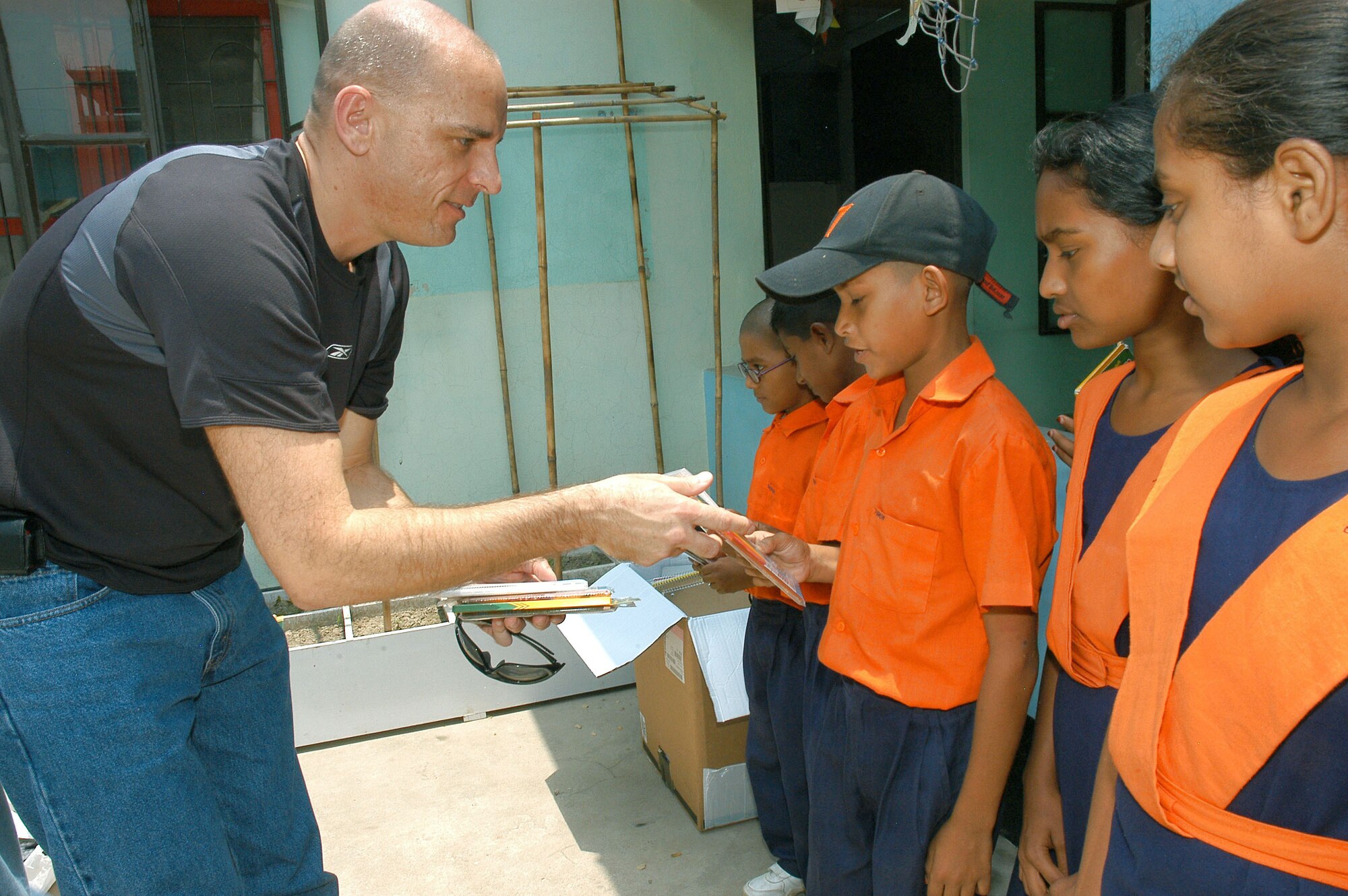 Senior Master Sgt. Jerry Wilkerson distributes school supplies at Eglal's ABC School April 27 in Dhaka, Bangladesh. Sergeant Wilkerson and other members of the 353rd Special Operations Group are training with the Bangladesh air force during Exercise Teak Buffalo. (U.S. Air Force photo/Master Sgt. Marilyn Holliday)                          