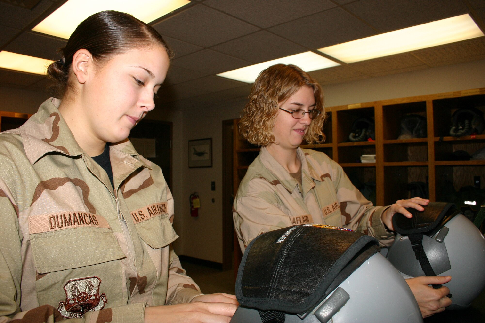Airman 1st Class (A1C) Leilani Dumancas and Airman (Amn) Kari Raaflaub of the 148th Fighter Wing, Duluth, Minn. Air National Guard, Life Support Shop repair helmets at their desk inside the Operations building on January 20, 2007.  A1C Dumancas and Amn Raaflaub were cleaning and repairing the equipment prior to a training flight.  (U.S. Air Force photo by Senior Airman Donald Acton)(Released)