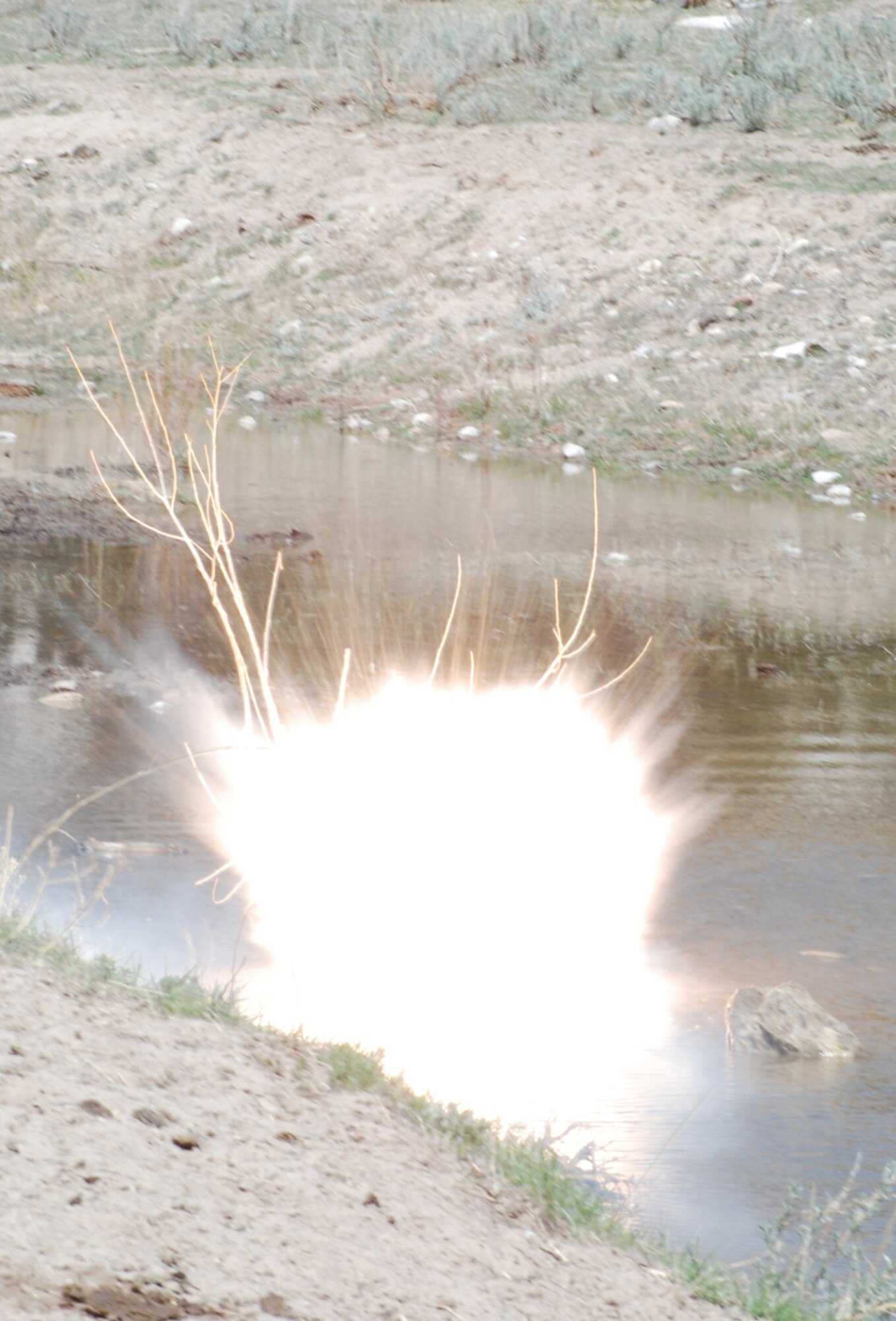 A ground burst simulator explodes to begin the third event of the Guardian Challenge April 30 at Camp Guernsey. The 37th Helicopter Squadron and the 90th Security Forces Group work together to secure a vehicle that was attacked. There were eight opposing forces that shot blanks at the Airmen and ground burst simulators exploded throughout the event (U.S. Air Force photos/Staff Sgt. Chad Thompson).