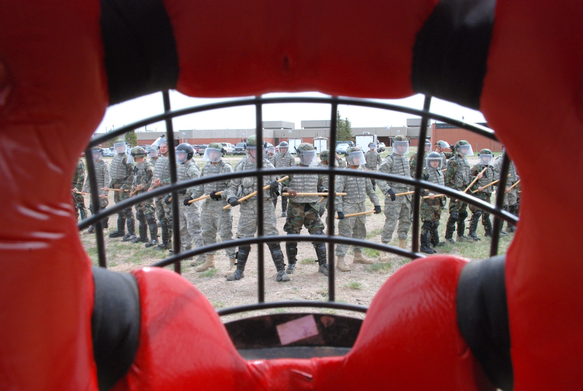The 90th Missile Security Forces Squadron Flight One Airmen line up into a wedge formation during their confrontation training April 28 in the field behind Bldg. 152. The training is designed to give the security forces Airmen a more realistic feel of crowd control. The “aggressors” dressed in red suits to protect them from any hits from the batons (U.S. Air Force photos/Staff Sgt. Chad Thompson).
