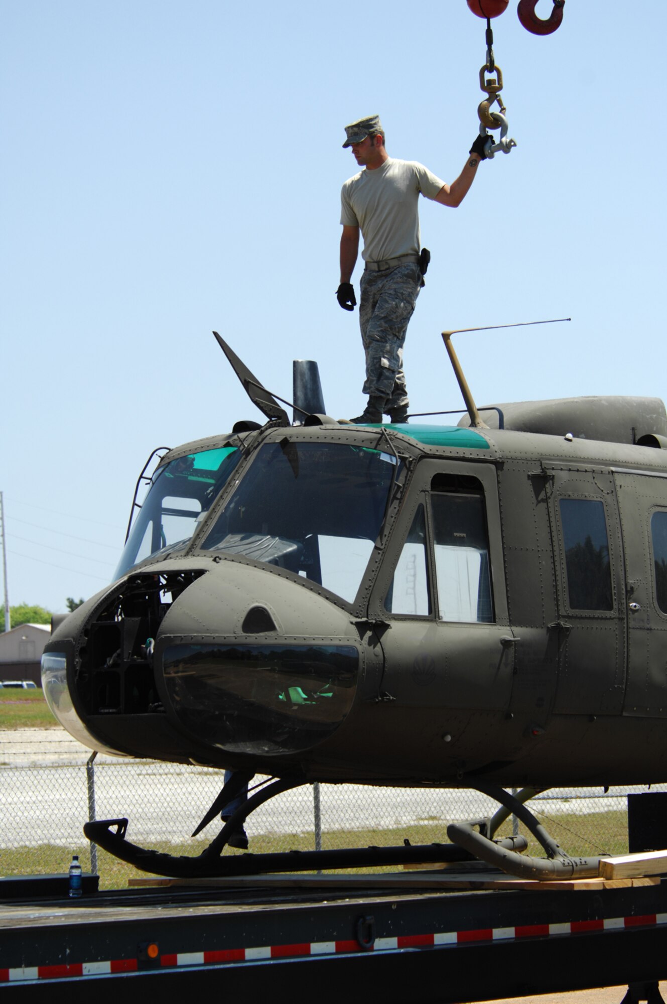 FT. RUCKER, Al. - Staff Sgt. Jeffrey Huber, 23rd Logistics Readiness Squadron, stands on top of a decomissioned UH-1 Huey helicopter fuselage, after it was loaded onto a truck at Fort Rucker, Al. April 30.  Five UH-1 helicopter fuselages will be transported by truck to Moody and used to enhance combat search and rescue readiness. (U.S. Air Force photo by Staff Sgt. Joshua T Jasper)