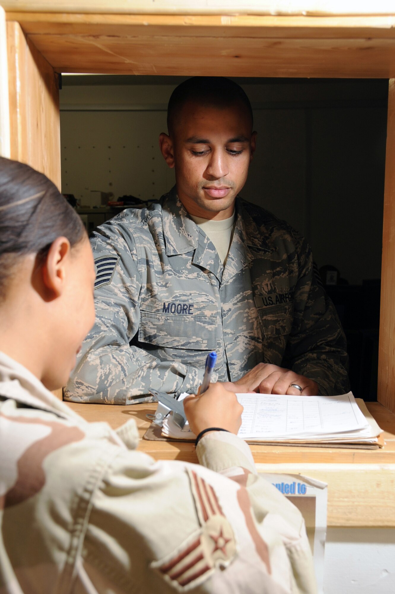 ALI BASE, Iraq -- Tech. Sgt. William Moore, 407th Expeditionary Communications Squadron noncommissioned officer in charge of the help desk, assist Senior Airman Tessa Jackson in filling out a work order request here May 1.   Sergeant Moore is officially a satellite communications and wideband technician, but while deployed, he manages the communication's focal point or "help desk."  Sergeant Moore is deployed from Tinker AFB, Okla.  (U. S. Air Force photo / Tech. Sgt. Sabrina Johnson)