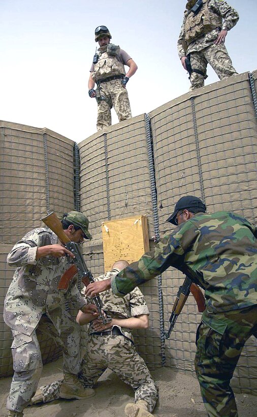 An Iraqi police officer hands off his weapon to his overwatch partner
