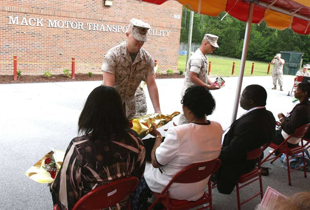 Marines present flowers to the family members of Master Sgt. Kenneth N. Mack here May 5.  Mack’s family was in attendance at a building dedication ceremony where the II Marine Expeditionary Force Headquarters Group motor transport facility was dedicated in honor of Mack’s service.