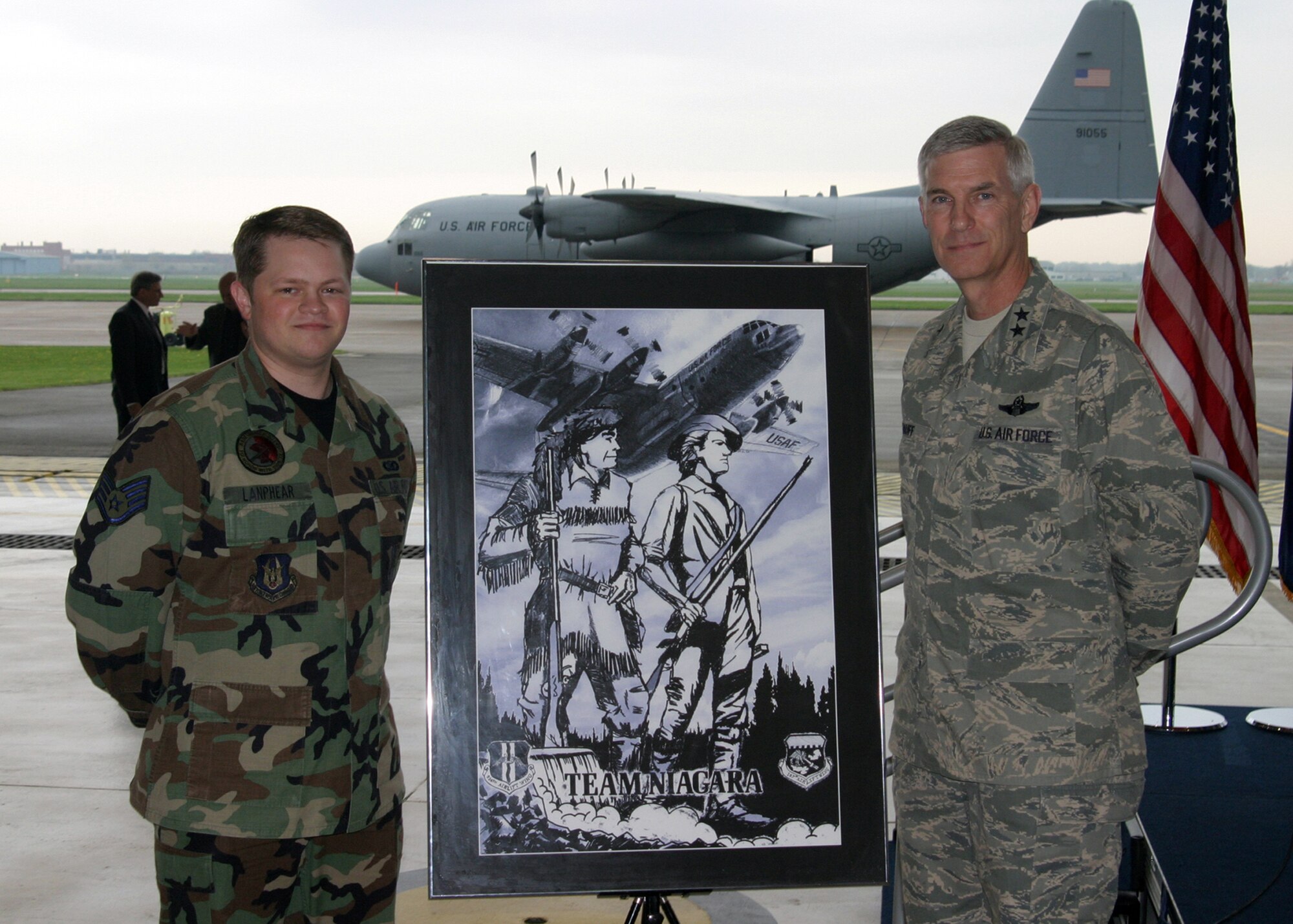 NIAGARA FALLS AIR RESERVE STATION, N.Y. - Staff Sgt. Daniel Lanphear (left), Air Force Reserve and Maj. Gen. Robert Knauff, commander of the New York Air National Guard pose in front of Staff Sgt. Lanphear's hand-sketched artwork which portrays the unity between the Guard and Reserve at Niagara.  The Frontiersman on the left side of the artwork represents the 914th Airlift Wing (AFRC) and the Minuteman on the right represents the 107th Airlift Wing (NYANG).  Standing over Niagara Falls, they symbolize Citizen Airmen united in defense of our nation.  The C-130 represents the units' combined combat flying mission and this artwork commemorates the first ever Reserve/Guard C-130 association.  (U.S. Air Force photo / Tech. Sgt. Christopher Boswell)