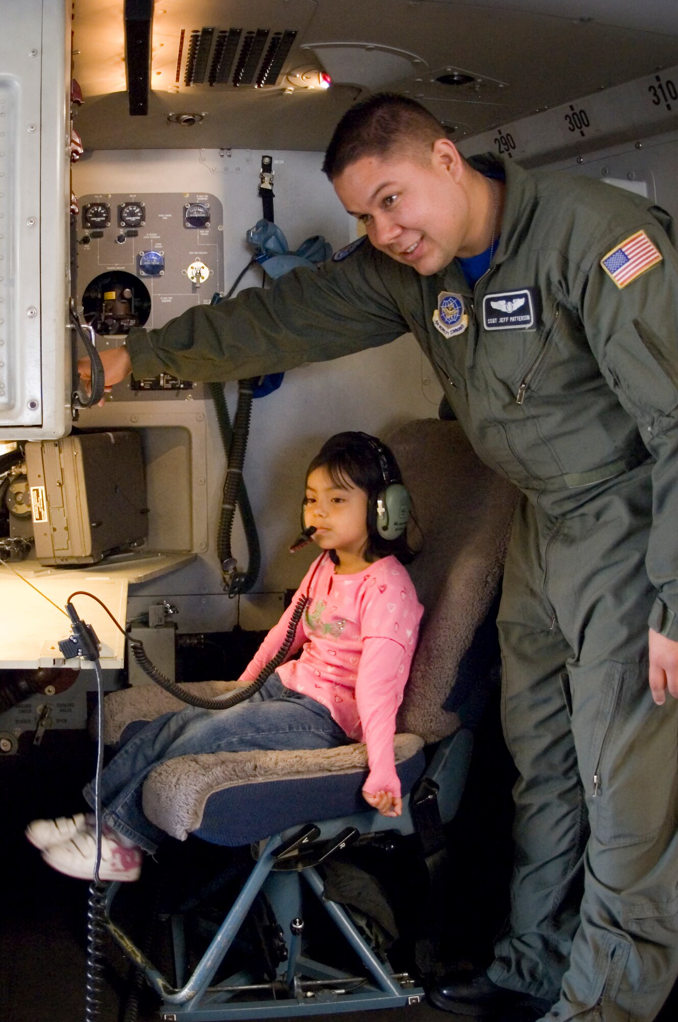 Staff Sgt. Jeff Patterson, a loadmaster with the 8th Airlift Squadron, adjusts the volume on his headset for five-year-old Iris Noquez.