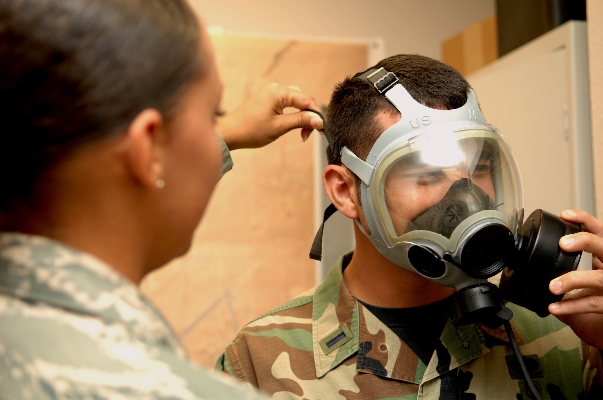 HOLLOMAN AIR FORCE BASE, N.M. -- Airman 1st Class Amber Green, 49th Aeromedical Dental Squadron, helps 1st Lt. Scott King, also 49 ADOS, tighten the straps on his gas mask May 5 at the medical clinic here. Airman Green is performing a gas mask fit test which ensures the owner has the right size mask and detects any leaks in the mask. (U.S. Air Force photo by Airman Sondra M. Wieseler)