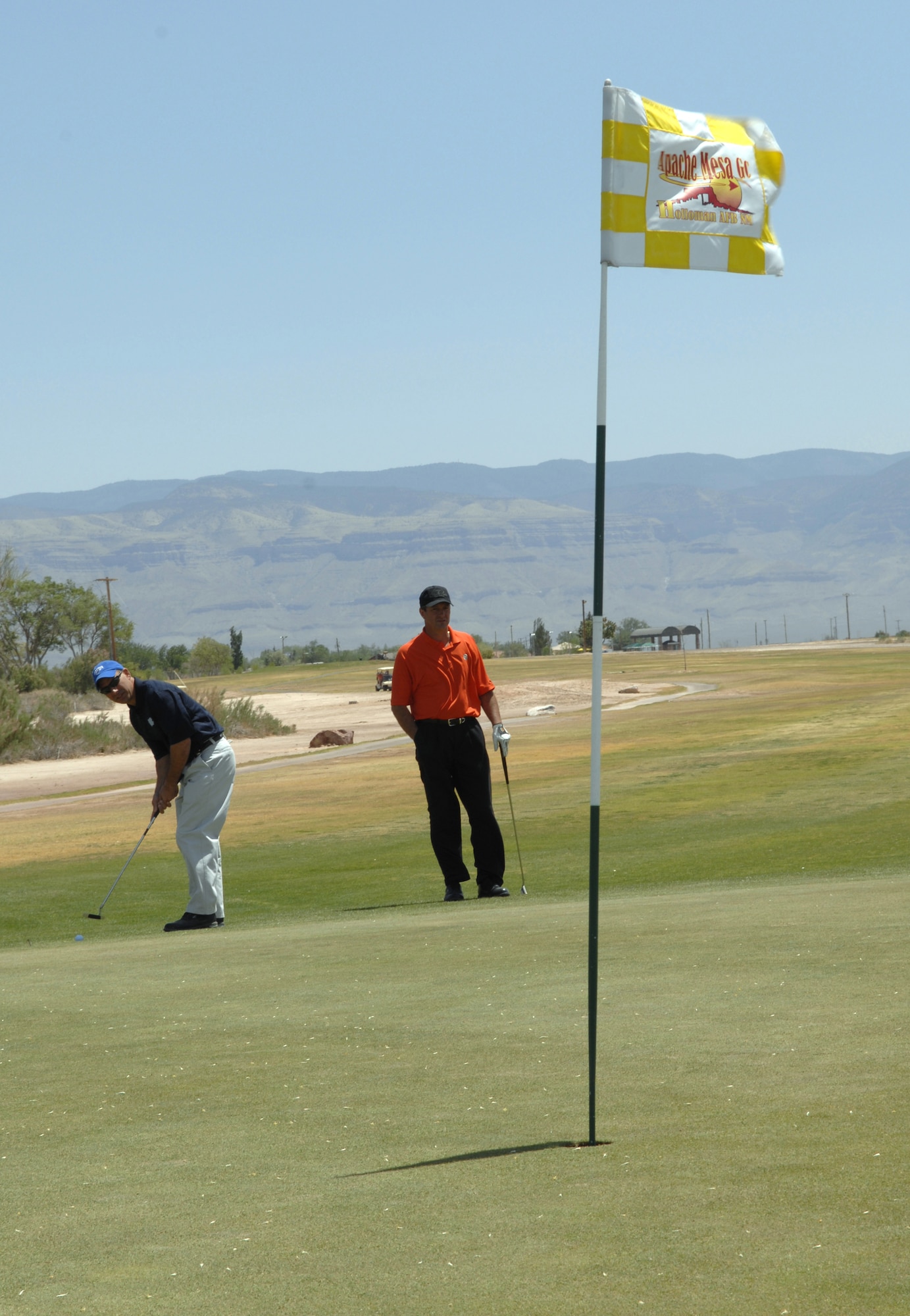 HOLLOMAN AIR FORCE BASE, N.M. -- Colonel Jeff Harrigian, 49th Fighter Wing commander, prepares to tee off while Mark Doinoff, the director of golf at the Apache Mesa Golf Course, observes. Colonel Harrigian and Mr. Doinoff are one of 22 teams participating in the two-man scramble Committee of 50 Golf Tournament at the golf course here.. (U.S. Air Force photo/Airman Sondra Wieseler)