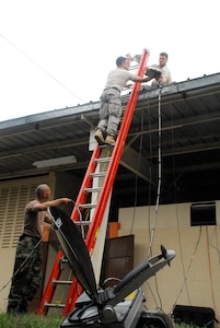 Establishing communication at their home-away-from-home, a Salvadoran Air Force facility, (left to right) Tech. Sgt.  Mike Vaughn, Capt. Ernesto Garcia and Tech Sgt. Jeff Scott run antennas to the roof of the facility. (U.S. Air Force photo by Tech. Sgt William Farrow)