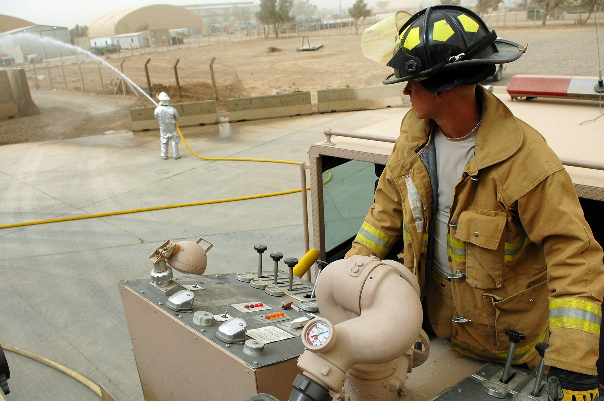 Army Spc. James Taylor operates the pump panel during hose advancement and pump training with Airman 1st Class Adam Baumgardner April 29 at Balad Air Base, Iraq. The firefighters here train together and share critical skills and knowledge everyday. Specialist Taylor is an 8th Ordnance Company firefighter deployed from Fort Bragg, N.C., and Airman Baumgardner is a 332nd Expeditionary Civil Engineer Squadron firefighter deployed from Malmstrom Air Force Base, Mont. (U.S. Air Force photo/Senior Airman Julianne Showalter) 
