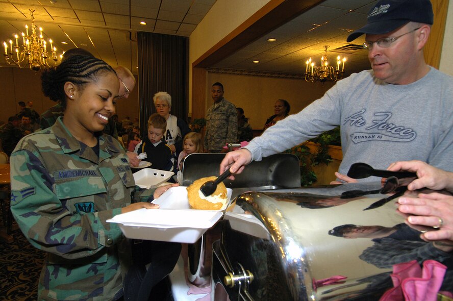 MINOT AIR FORCE BASE, N.D. -- Airman Simret AmDemichael, 5th Communications Squadron, smiles as she takes a break from work to eat breakfast, served up by Chief Master Sgt. Robert C. Rohn, 5th Maintenance Group here May 2.  The Chief's group provides this breakfast twice a year to help the enlisted corps of Minot AFB.  (U.S. Air Force photo by Airman 1st Class Kelly Timney)