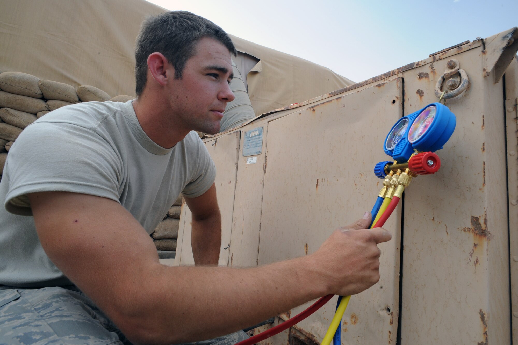 ALI BASE, Iraq -- Airman Tyler Howells, 407th Expeditionary Civil Engineering Squadron air conditioning apprentice, reads manifold gages to check the refrigerant levels of an air conditioning system here May 6.  He was selected as the 407th Air Expeditionary Group Warrior of the Week for the week of May 5 and is deployed from Eielson AFB, AK. (U. S. Air Force photo / Tech. Sgt. Sabrina Johnson) 
