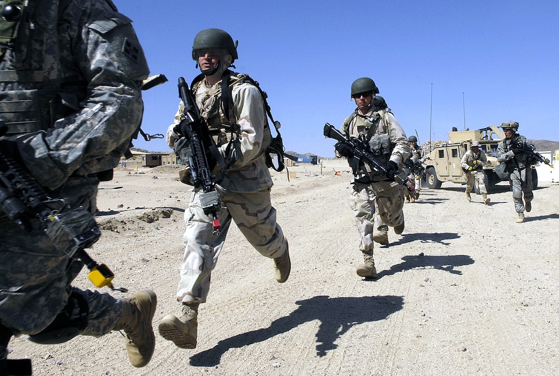 U.S. soldiers run toward a mock Iraqi village during an exercise at the National Training Center on Fort Irwin, Calif., May 1, 2008. Simulated improvised explosive devices, role-playing "villagers," and Hollywood make-up artists, make the pre-deployment training as realistic as possible.