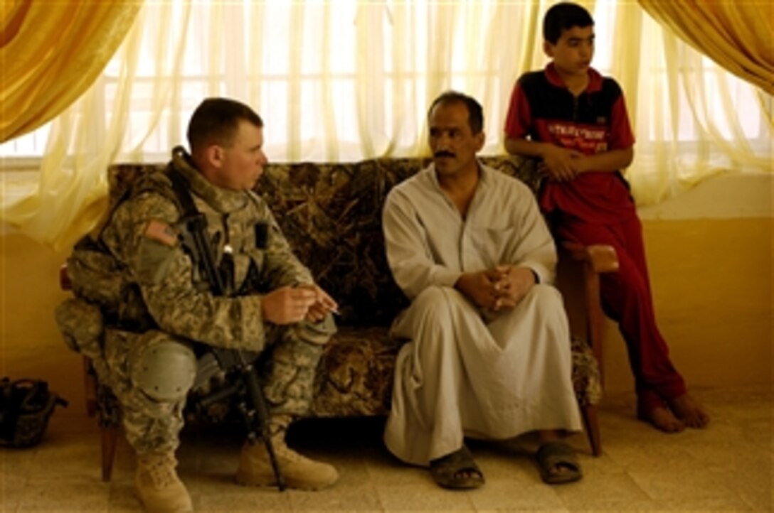 U.S. Army Capt. Paul Goodfellow (left) speaks to a family about activity in the city and any concerns they may have during a cordon and knock operation in Tikrit, Iraq, on May 2, 2008.  Goodfellow is assigned to Alpha Company, 1st Special Troop Battalion, 1st Brigade Combat Team, 101st Airborne Division.  