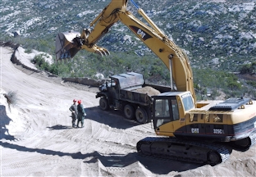 Under the shadow of a large excavator, U.S. Air Force Staff Sgt. Mark Ellis and Master Sgt. Chris Blackwell discuss plans to smooth out this dangerous stretch of hairpin turns that hampers U.S. border patrol officers in their efforts to secure the border near Campo, Calif., May 1, 2008, The two are assigned to the 201st RED HORSE Squadron. 