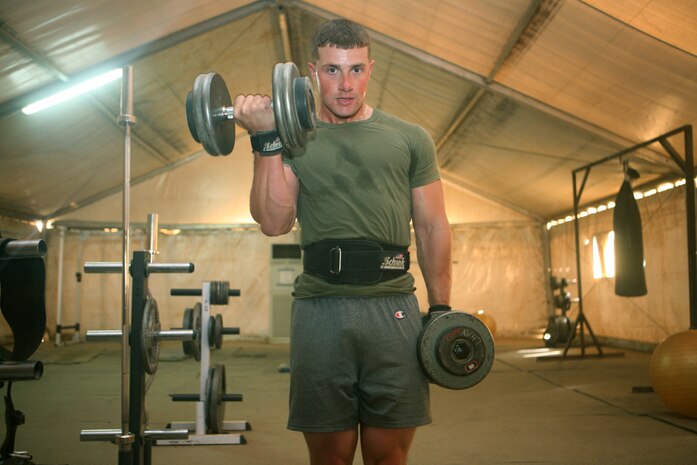 Lance Cpl. Lance Cpl. Christopher J. Talbot, a scout with Charlie Company, 2nd Light Armored Reconnaissance Battalion, Regimental Combat Team 5, performs a standing-curl set during his routine workout at Camp Korean Village, Iraq, May 6. The amateur body builder placed second in his first competition before joining the Marine Corps.  He qualified for nationals in amateur body building, but instead of proceeding to nationals he embarked on a different journey by enlisting in the U.S. Marine Corps.