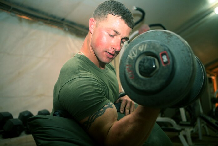 Maintaining his arm strength and definition, Lance Cpl. Christopher J. Talbot, a scout with Charlie Company, 2nd Light Armored Reconnaissance Battalion, Regimental Combat Team 5, curls a 50 pound dumbbell during one of his weight lifting sessions at Camp Korean Village, Iraq, May 6. Once Talbot was in the ninth grade, he began working out every single day to mold himself into a body builder and hopes to one day become a professional body builder.