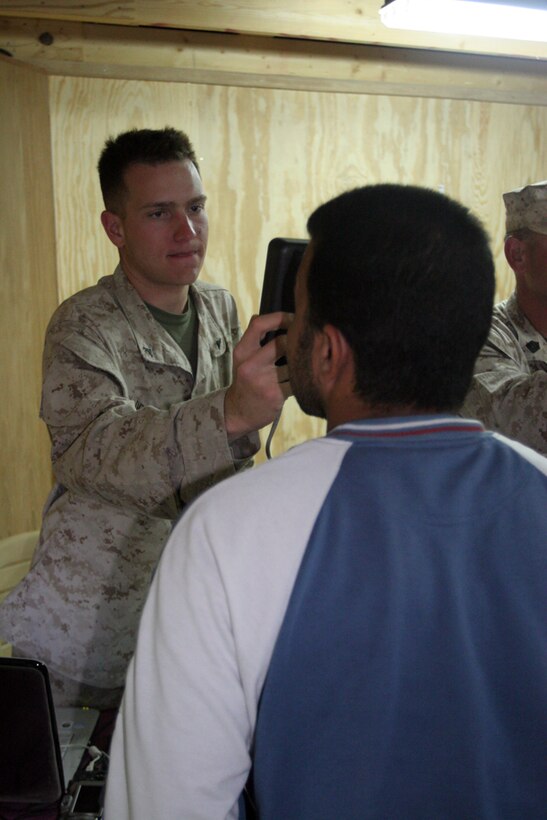 Lance Cpl. Joseph T. Delorefice, 19, from Lancaster Penn., who is a motor transport operator and civil affairs representative with Civil Affairs Team 1, Detachment 1, 2nd Battalion, 11th Marine Regiment, Regimental Combat Team 5, scans the eyes of an Iraqi who is trying to get an identification badge at the Civil Military Operations Center, Haditha, Iraq, May 6. The badges are part of a system that will track if anyone has a history of anti-Coalition forces activity.