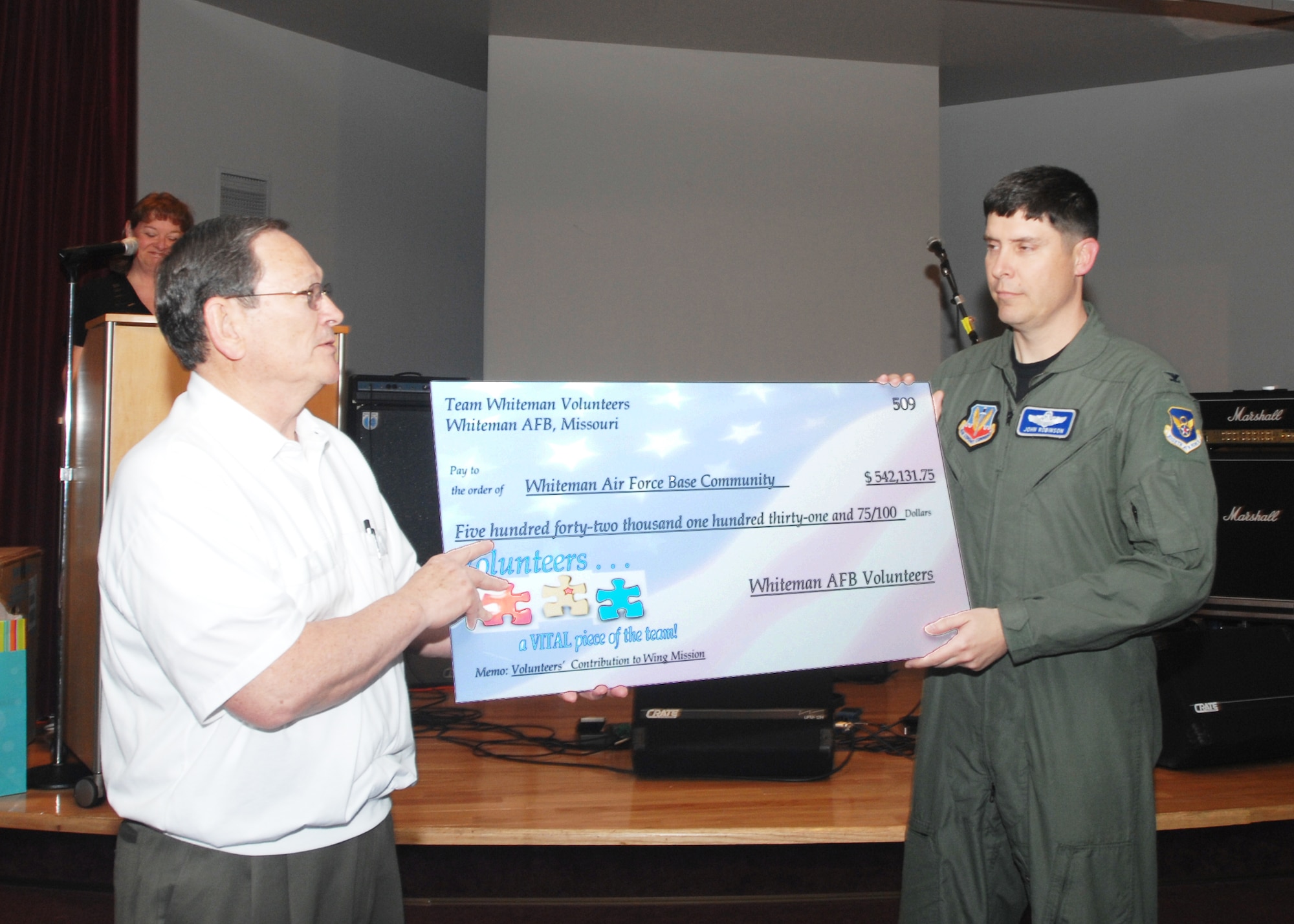 WHITEMAN AIR FORCE BASE, Mo. - Jack Bryant, 509th Airman and Family Readiness Center director, presents a check to Col. John Robinson, 509th Bomb Wing vice commander, during the annual volunteer reception April 29. The check, written for $542,131.75, is an actual check for money, rather a representation of how much the work volunteers have accomplished in the past year is worth. During the reception, volunteers were also recognized for their outstanding efforts and service to the Whiteman Community. (U.S. Air Force photo/Tech. Sgt. Samuel Park)