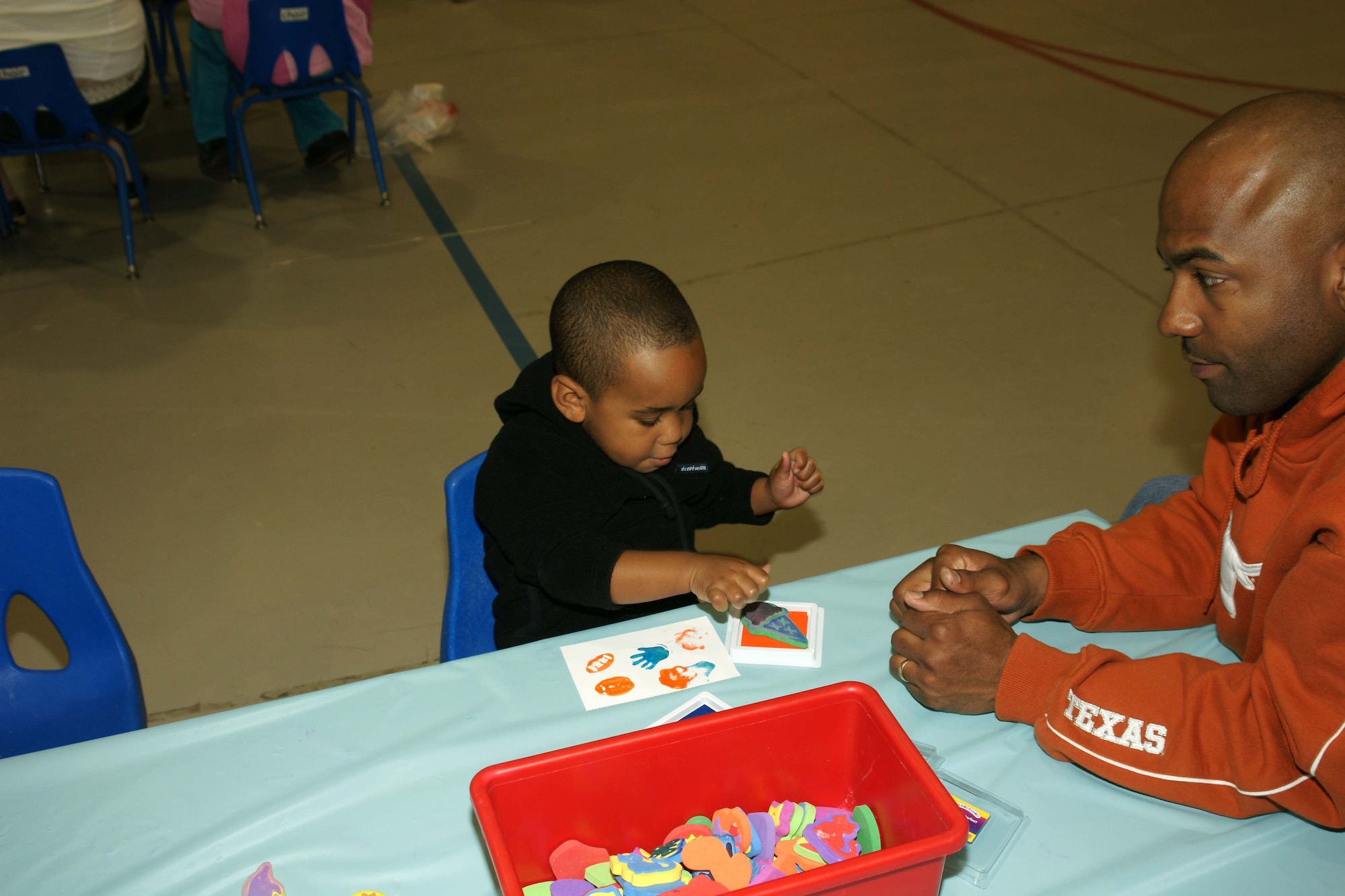 Jayden Johnson (left) and his father, Staff Sgt. Bryan Johnson, 55th Wing protocol, sprinkles up his ice cream cone at the community center. Families enjoyed this and other hands-on craft activities during this year's family fair. (U.S. Air Force Photo By/Bobby Baker)