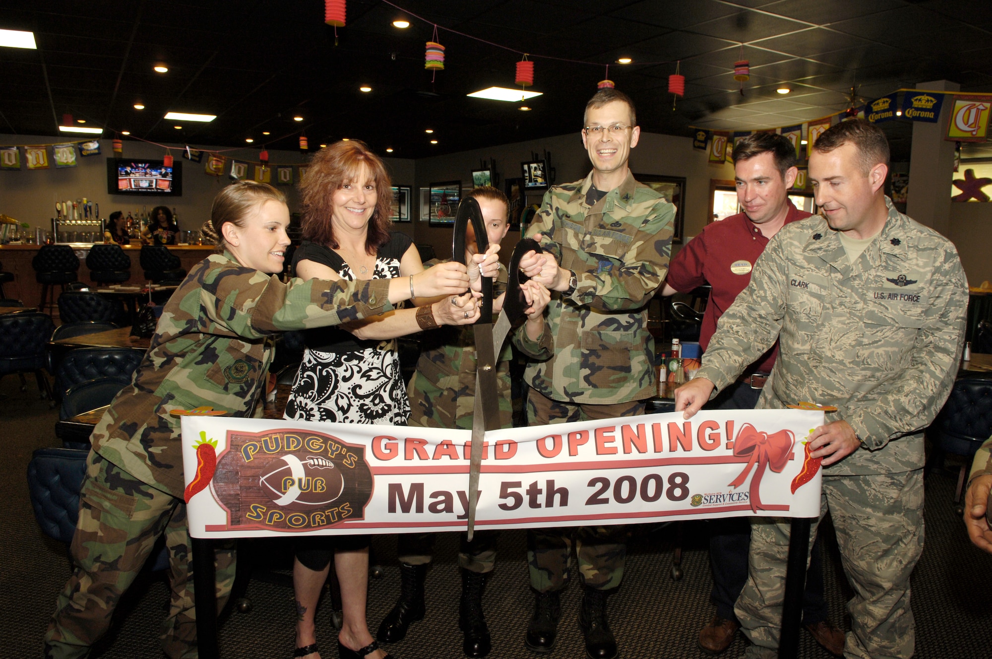 Left to right, 2nd Lt. Julie Mages, 305th Civil Engineer Squadron Simplified Acquisition of Base Engineer Requirement flight chief, Margaret Balestrieri, The Club manager, Senior Airman Deanna Stowe, 305 CES SABER project manager, Col. Michael Hutchison, 305th Mission Support Group commander, Daniel McDermott, business activities flight chief, and Lt. Col. John Clark, 305th Services Squadron commander, cut the ribbon during the grand re-opening of Pudgy’s Sports Pub May 5 here. Afterward, the celebration continued with a Cinco De Mayo party. (U.S. Air Force photo/Kenn Mann)
