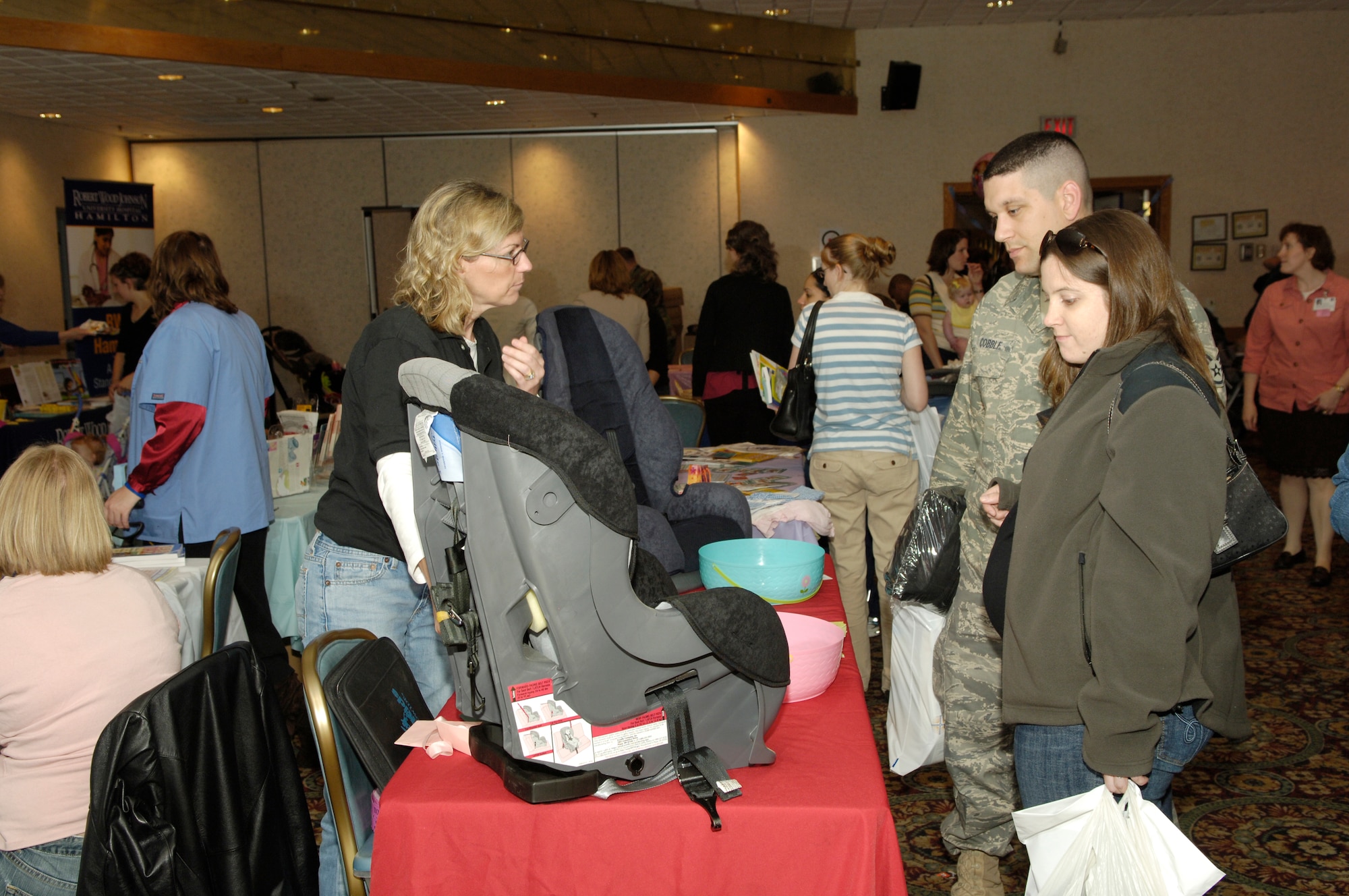 Maureen Donnelly, a registered nurse with Safe Kids Southern New Jersey, shows Staff Sgt. Rick Cobble, 305th Communications Squadron, and his wife, Julie, how to properly utilize a child care seat during the Baby & Toddler Expo May 2 at The Club here. More than 30 vendors participated in the expo to provide support to military families and highlight the programs and products available for children. (U.S. Air Force photo/Kenn Mann)