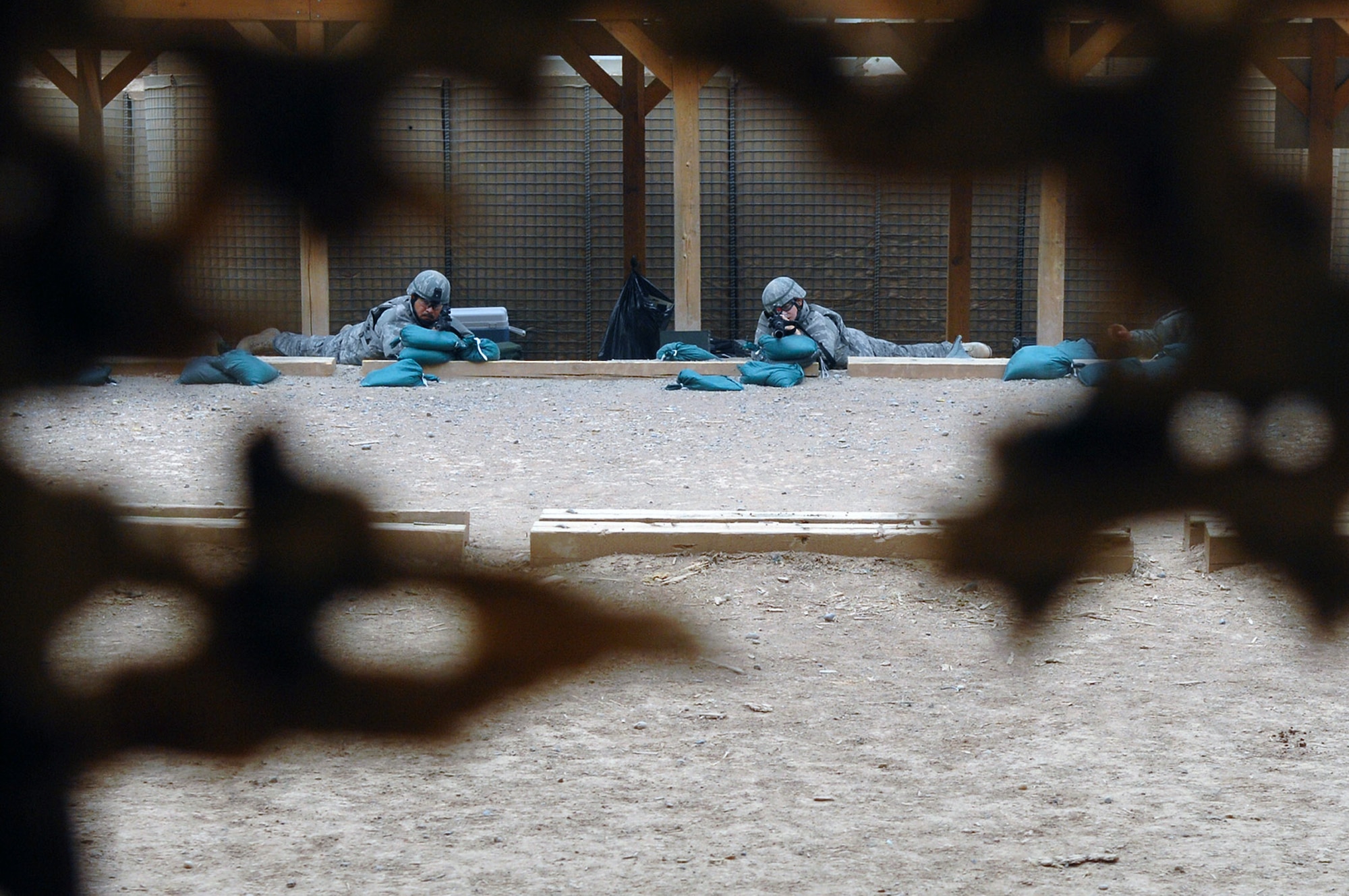 Airmen from the 332nd Expeditionary Security Forces Squadron adjust their defensive fighting positions before shooting live rounds at silhouette targets April 30 at Balad Air Base, Iraq. The target simulates different distances by using various sized silhouetted figures. (U.S. Air Force photo/Senior Airman Julianne Showalter) 
