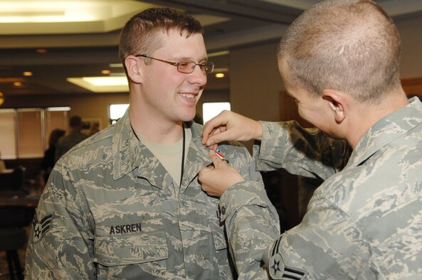 Airman 1st Class Adam Satterfield (right), 509th Security Forces Squadron, pins a ribbon to Senior Airman Bradley Askren during the Whiteman Warrior Welcome Home celebration April 30 held at Missions End. The ribbon symbolizes the service given during his deployment. (U.S. Air Force photo/Senior Airman Jessica Snow)