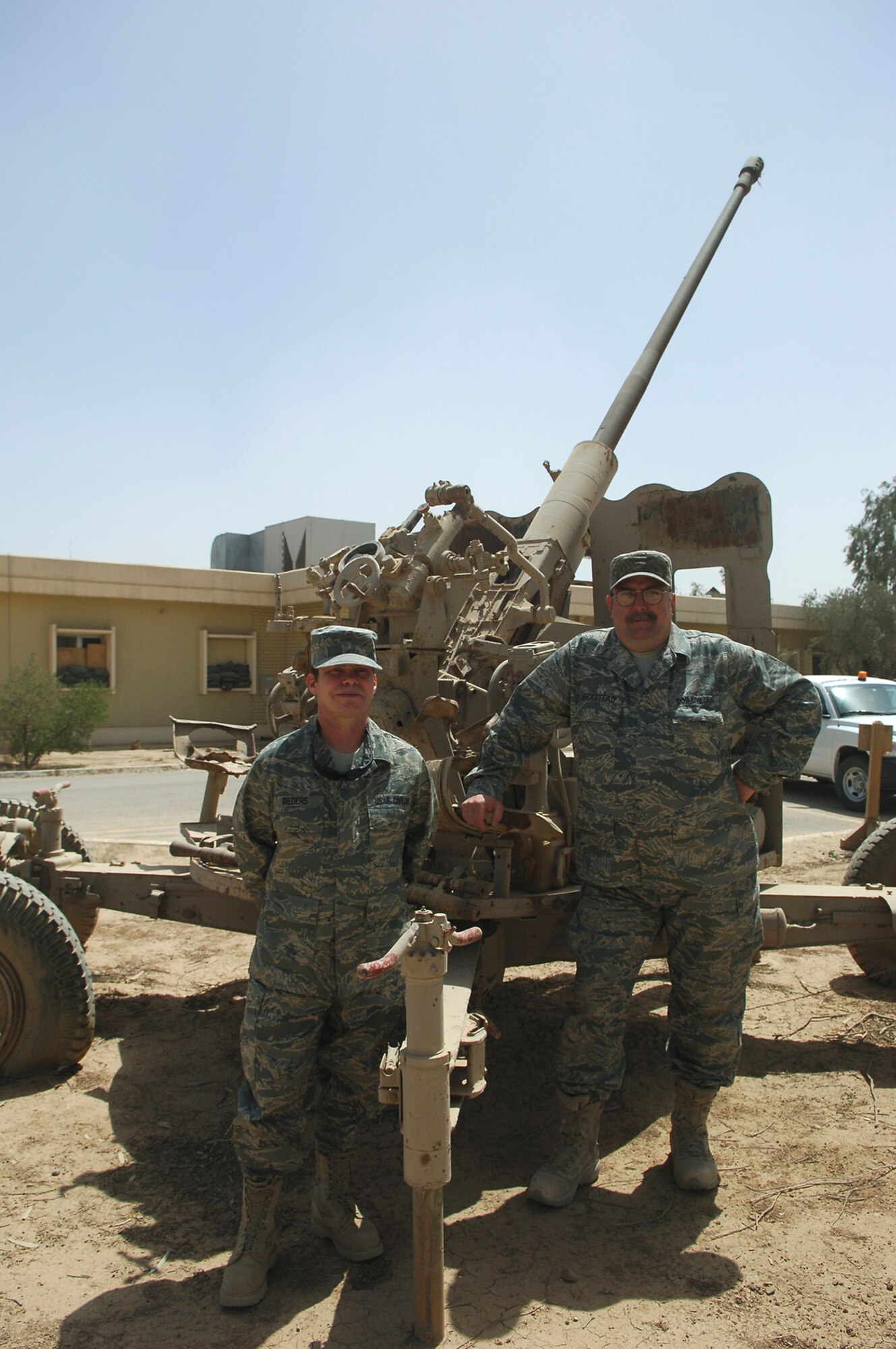 BALAD AIR BASE, Iraq -- Doug Beckstead (right) and Kevin Rieders, both 332nd Expeditionary Air Wing historians, stand in front of an anti-aircraft weapon used by the Iraqi military prior to the fall of the Saddam Hussein regime that remains on the base, here May 7. Mr. Beckstead and Mr. Rieders are Department of Defense civilians deployed to Balad in support of Operation Iraqi Freedom just like their military counterparts. Mr. Beckstead is deployed from Elmendorf Air Force Base, Alaska; Mr. Rieders is deployed from Spangdahlem Air Base, Germany. (U.S. Air Force photo /Staff Sgt. Mareshah Haynes)
