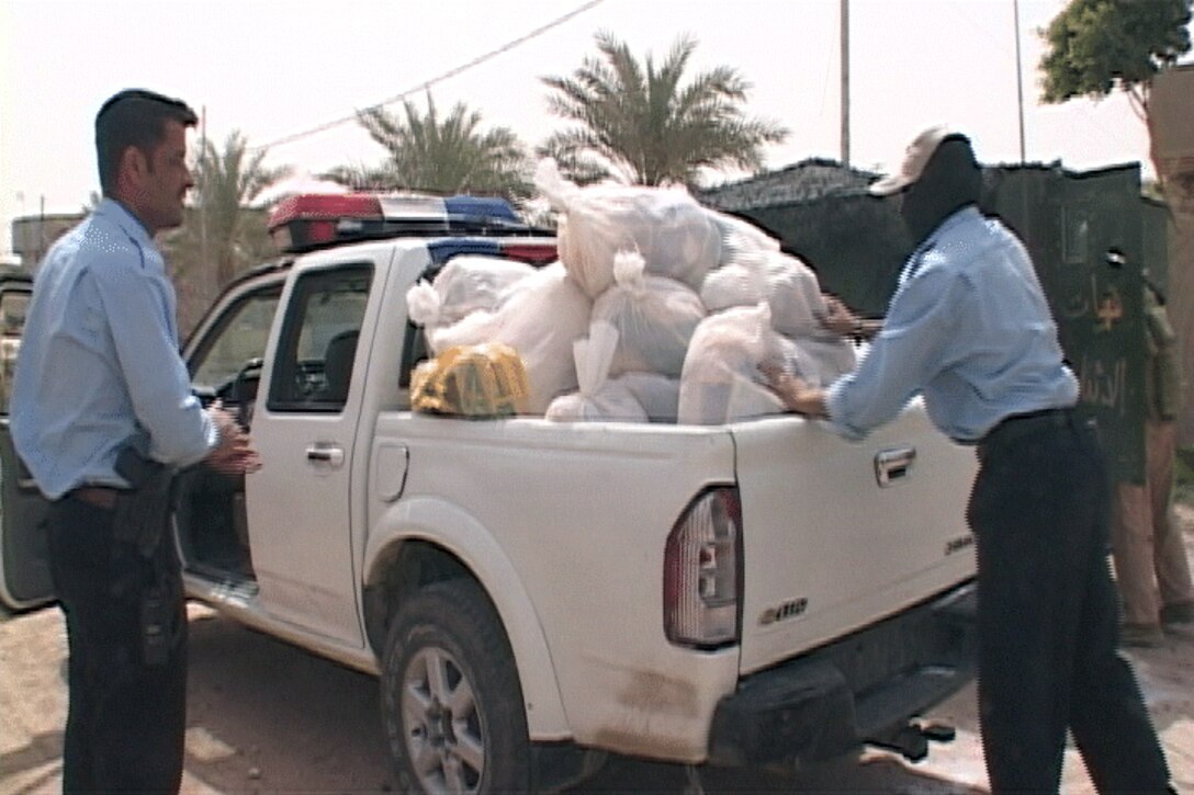 Iraqi Police load a vehicle with food bags to distribute to local residents who are less fortunate during a patrol here May 7. IPs are performing daily tasks such as this in a leading role to establish a stronger presence in the city. (Official U.S. Marine Corps photo by Cpl. Chris Lyttle) (RELEASED)