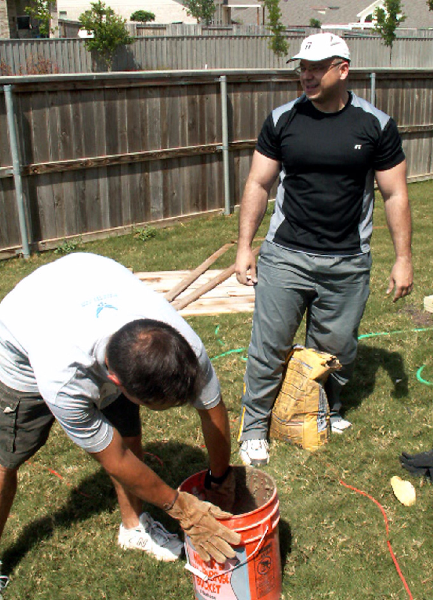 Master Sgts. Tracy Deason (left) and Angel Espinosa mix cement while participating in Operation Homefront April 30 in Cibolo, Texas. Volunteers from the Top 3 Association from Air Force Personnel Center from Randolph Air Force Base, Texas, helped craft a gate to provide better access between the front and back yards for Tech. Sgt. Israel Del Toro, an Airman recovering from wounds sustained during a roadside bombing in Afghanistan. Sergeants Deason and Espinosa are personnelists at AFPC. (U.S. Air Force photo/Master Sgt. Kat Bailey) 
