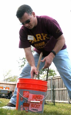 Master Sgt. Alex McCullough mixes cement to stabilize a fence post as part of a volunteer effort supporting Operation Homefront April 30 in Cibolo, Texas. Volunteers from the Top 3 Association from Air Force Personnel Center from Randolph Air Force Base, Texas, helped craft a gate to provide better access between the front and back yards for Tech. Sgt. Israel Del Toro, an Airman recovering from wounds sustained during a roadside bombing in Afghanistan. Sergeant McCullough is a personnelist at AFPC. (U.S. Air Force photo/Master Sgt. Kat Bailey)