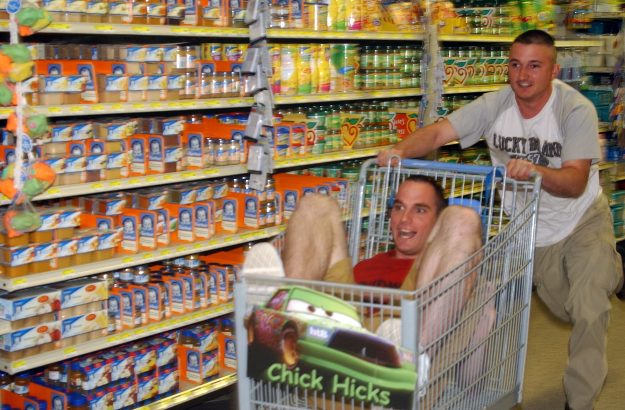 Airmen 1st Class Shon Hennigan, 741st Missile Security Forces Squadron member, races past jars of baby food at the base commissary with Airman 1st Class Drake Amtower, 741st MSFS member, in a shopping-cart drag race at the base commissary during "Single Airman's Night" May 4. (U.S. Air Force photo/Airman 1st Class Dillon White)