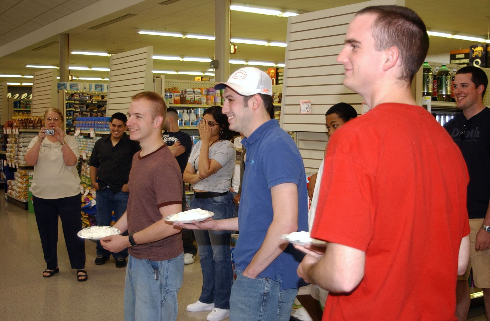 Airmen 1st Class Darby Rocheleau, and John Limberopoulos, 341st Missile Security Forces Squadron members, and Airman 1st Class Drake Amtower, 741st MSFS member, prepare to throw whipped-cream pies at Senior Master Sgt. Jeffrey Neutzling, 341st MSFS first sergeant, during "Single Airman's Night" at the base commissary. (U.S. Air Force photo/Airman 1st Class Dillon White)