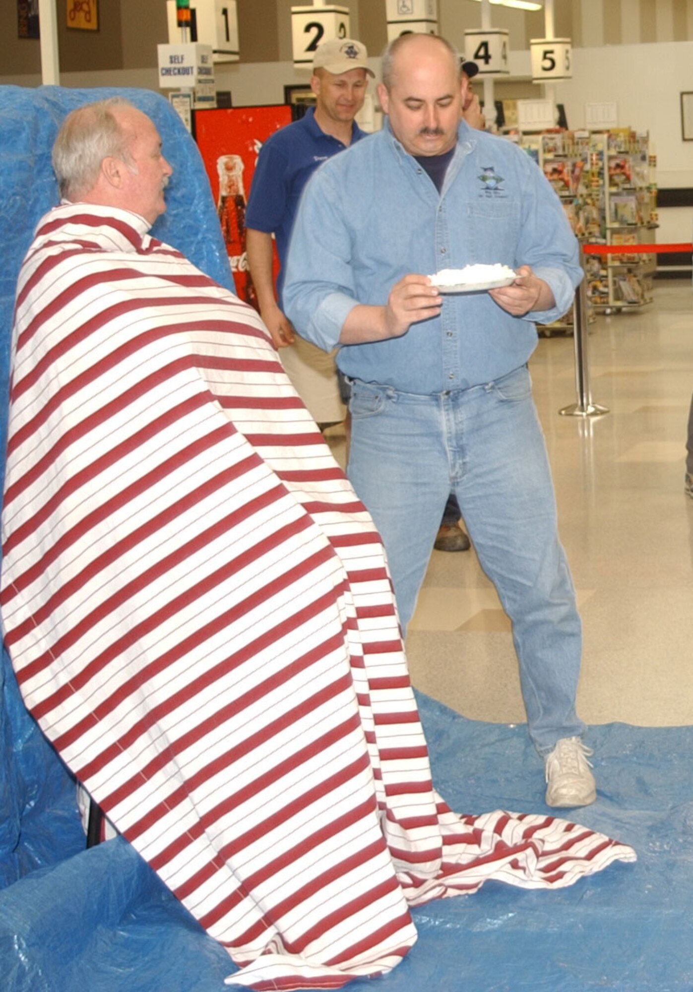 John Nelson, base commissary manager, prepares to receive a pie in the face from Senior Master Sgt. Jeffrey Neutzling, 341st Missile Security Forces Squadron first sergeant, during "Single Airman's Night" at the base commissary May 4. (U.S. Air Force photo/Airman 1st Class Dillon White)                            