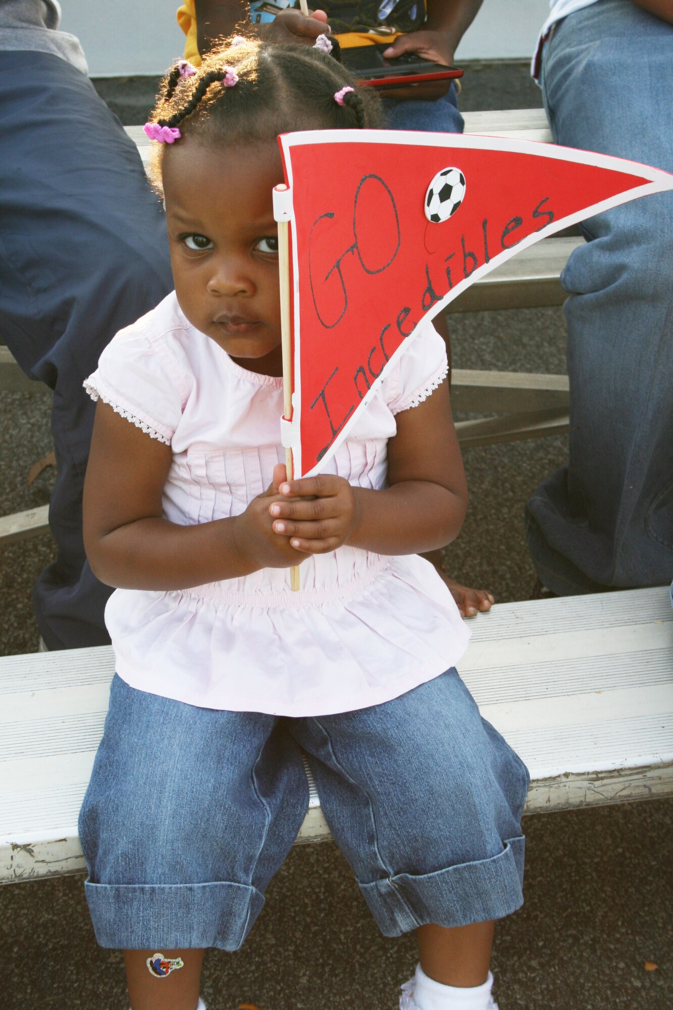 Zoriyah Menefee, 2, cheers for her big brother; Will Menefee, 8; who plays for the Incredibles. The homemade signs were made by Will and, the pair’s older brother, Kenny Menefee, 11. U. S. Air Force photo by Amanda Creel