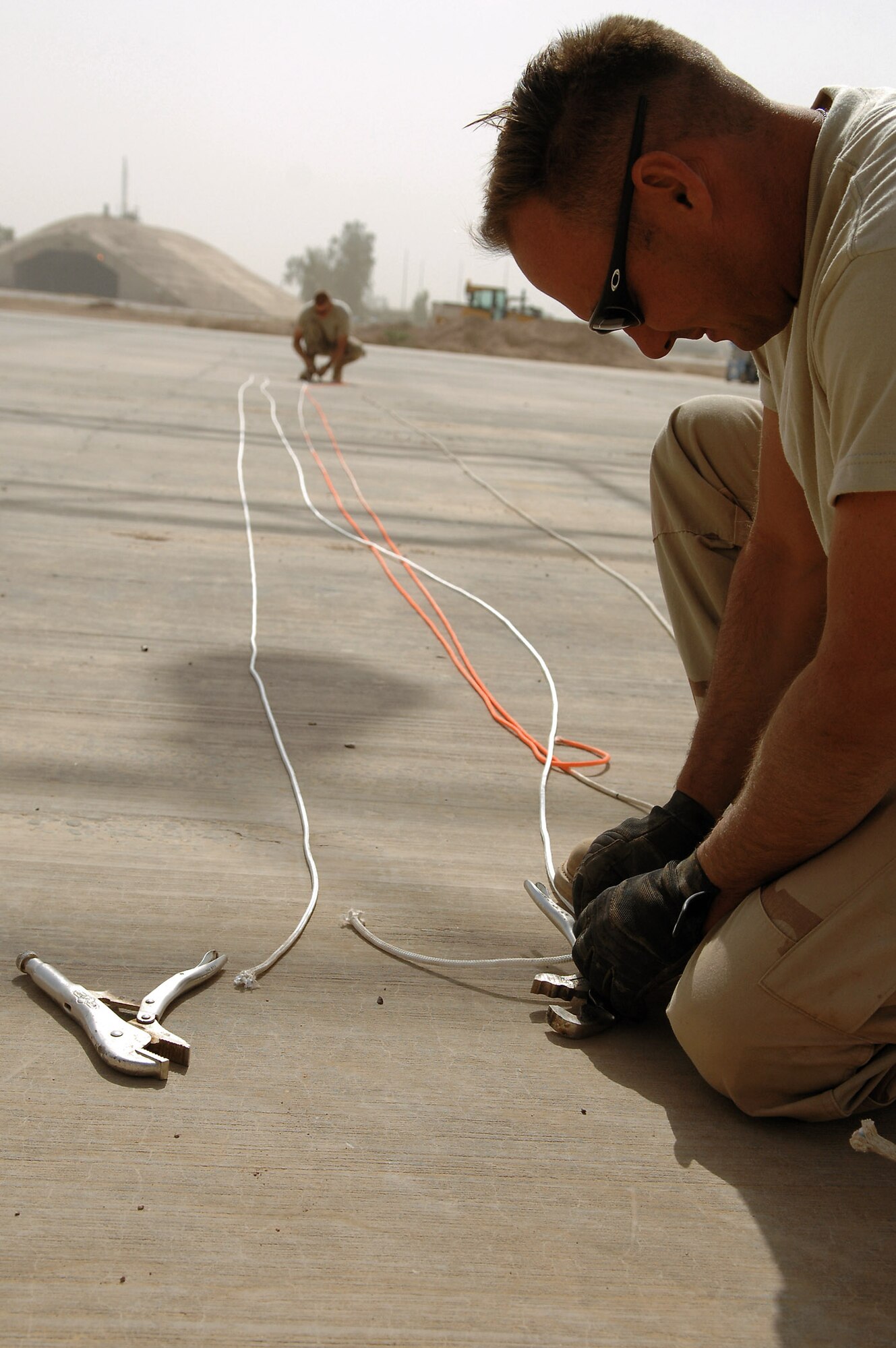 Tech. Sgt. Scott Greenwalt ties chase ropes to clamps May 7 at Balad Air Base, Iraq. The ropes are clamped onto the canopy while being raised to prevent the wind from damaging it. Sergeant Greeenwalt is a 332nd Expeditionary Civil Engineer Squadron structural engineer deployed from Ellsworth Air Force Base, S.D. (U.S. Air Force photo/Senior Airman Julianne Showalter) 
