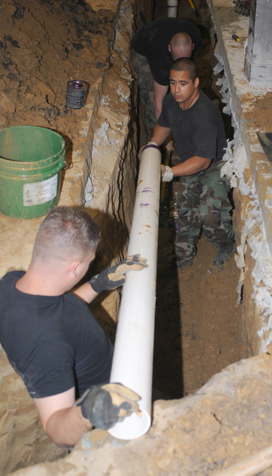 Staff Sgt. Rick Blayney, left, and Tech. Sgt. Emanuel Lopez, 81st Civil Engineer Squadron, lay pipe in the ground inside of Magnolia Dining Facility May 1.  Blocked, corroded cast-iron sewage pipes are being replaced.  As of Monday, the team has repaired the damaged drain lines and is cleaning and inspecting remaining drains and backfilling the trenches.  (U.S. Air Force photo by Kemberly Groue)