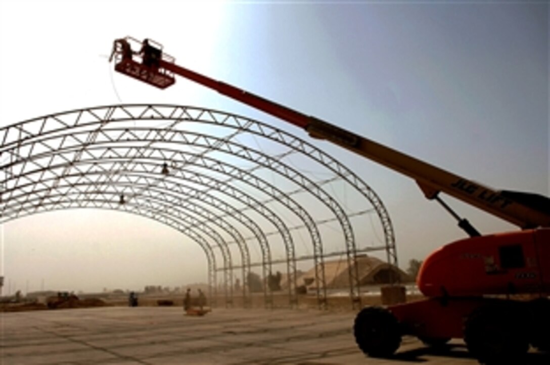 U.S. Air Force Staff Sgt. Karl Ferree and Senior Airman James Robison ride in a bucket truck to position lead ropes on a big top shelter at Balad Air Base, Iraq, May 7, 2008. The shelter can house various aircraft and equipment. Ferree is deployed from Luke Air Force Base, Ariz., and Robison is deployed from Malmstrom AFB, Mont. Both are structural engineers assigned to 332nd Expeditionary Civil Engineer Squadron. 