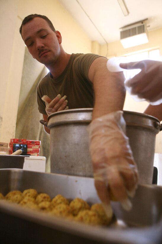 Cpl. Robert J. Hardesty, a food service specialist with Team Mustang, 2nd Light Armored Reconnaissance Battalion, Regimental Combat Team 5, places a stuffing ball in a pan before baking a batch for Marines of Team Mustang at Combat Outpost Patton, Iraq, May 8. Two Marines, Hardesty, and Lance Cpl. Thomas L. Jones, a scout with Team Mustang, provide chow twice a day for the Marines of Team Mustang, who conduct patrols in the western Anbar province.