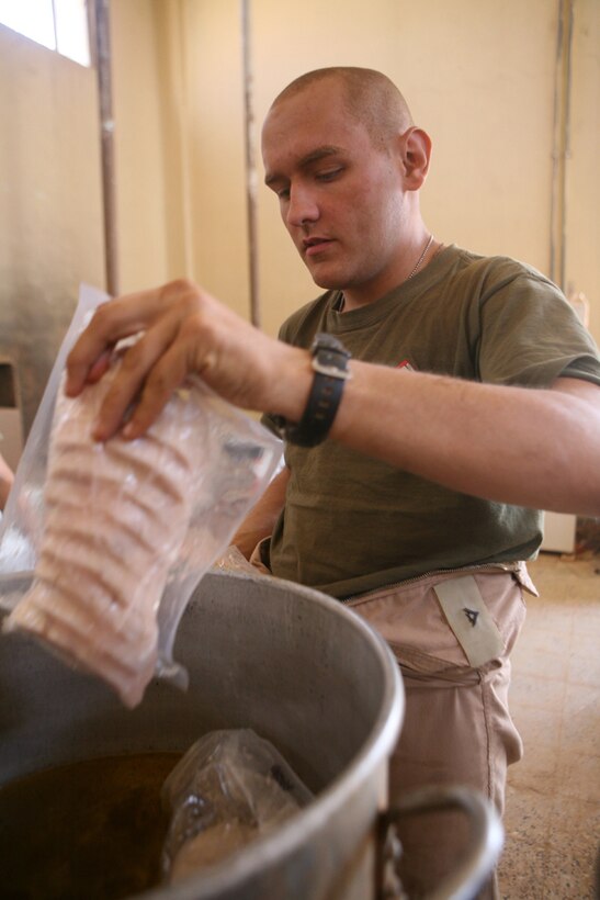 Dropping a batch of turkey cutlets into a pot, Lance Cpl. Thomas L. Jones, a scout with Team Mustang, 2nd Light Armored Reconnaissance Battalion, Regimental Combat Team 5, prepares a meal for other Marines with Team Mustang at Combat Outpost Patton, Iraq, May 8. Jones volunteered to assist the combat cook assigned to Tam Mustang because he enjoys cooking.