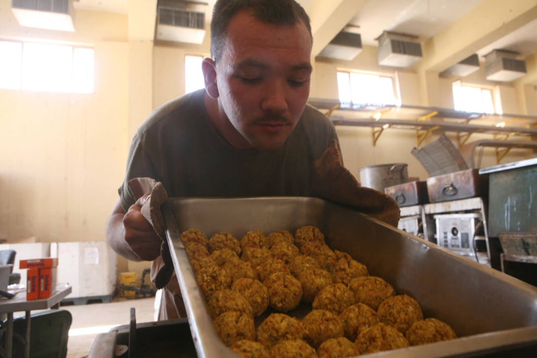 Cpl. Robert J. Hardesty, a food service specialist with Team Mustang, 2nd Light Armored Reconnaissance Battalion, Regimental Combat Team 5, smells a freshly baked pan of stuffing balls while cooking for Marines of Team Mustang at Combat Outpost Patton, Iraq, May 8. "The greatest feeling is when I see the faces of the Marines after they consume the meal and knowing how much they appreciated it," said Hardesty, 21, from Goshen, Ind. "It lets us know that we've made a huge difference in these men's lives."