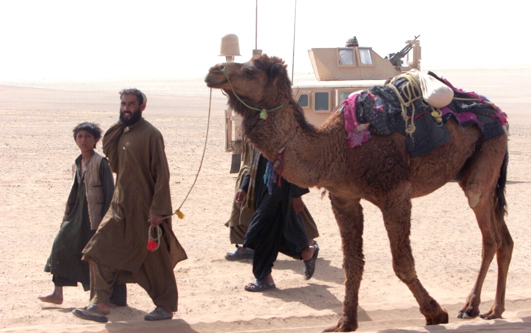 Travelers walk a camel past one of the Weapons Company, Battalion Landing Team 1st Battalion, 6th Marine Regiment, 24th Marine Expeditionary Unit, High Mobility Multipurpose Wheeled Vehicle's (HMMWV) at a vehicle control point in the Garmsir district. They set up a vehicle control point to deny Taliban fighters a key supply route.